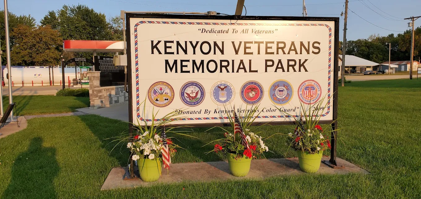 The Kenyon Veterans Memorial Park sign, dedicated to all veterans, carrying the seals of the six services